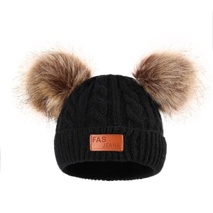 Detail view of black cable knit baby hat featuring double brown faux fur pom poms