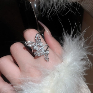 Detail of elegant butterfly ring with pavé crystals on finger over fur sleeve