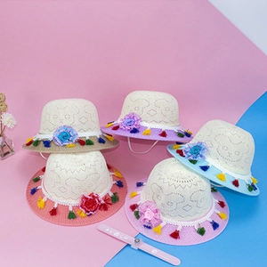Close-up of colorful straw sun hats for kids with floral details and fringe trim