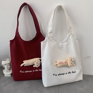 Detail of canvas tote bags with plush cat charm and embroidered English lettering