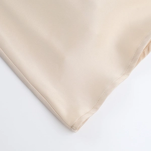 Gros plan sur la texture satinée champagne et l'ourlet à double couture de la robe