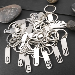 Polished silver metal alphabet keychains with hollowed letter charms on black textured background