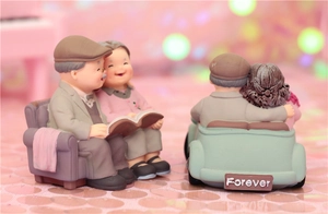 Detail of elderly couple resin figurines reading on sofa and driving a blue car
