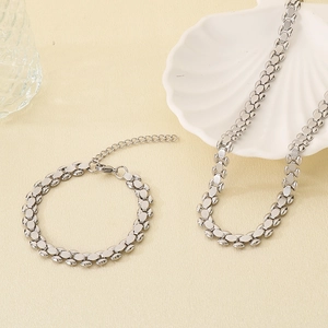 Silver-toned chain necklace and bracelet set with textured links on a shell plate