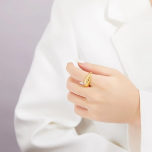 Detail of a vintage golden croissant dome ring with a polished ribbed texture on a finger