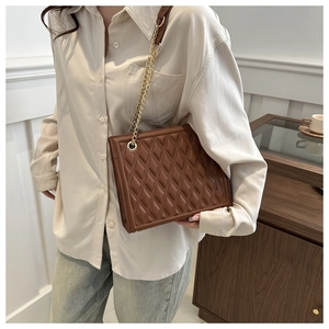 Brown quilted chain bag shown on model featuring a golden metal strap and leather texture