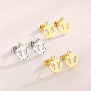 Close-up of gold and silver anchor earrings with tiny rhinestones on a white surface