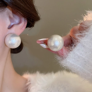 Gros plan de grandes boucles d'oreilles perles blanches rondes portées à l'oreille