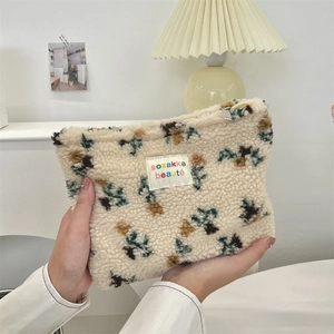 Detailed texture of plush fleece makeup bag with floral embroidery and label