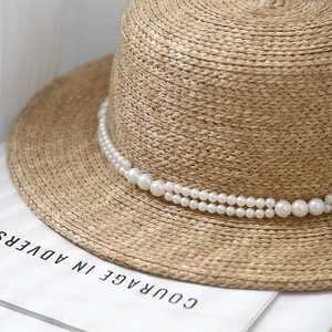 Elegant flat top straw hat with double-layered pearl chain from a 45-degree angle view