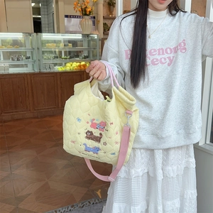 Detail of yellow quilted tote bag with cute cat embroidery and pink strap in a cafe