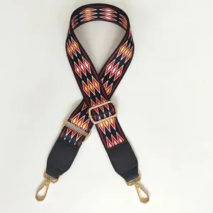 Detail of red diamond woven wide bag strap with black leather ends and gold metal hooks