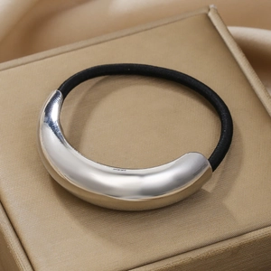 Macro detail of silver moon crescent metallic hair tie on a golden jewelry box