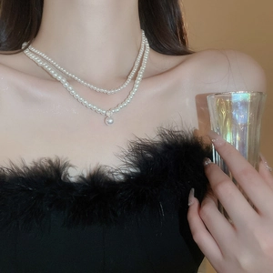 Close-up of double-layer pearl necklace with a teardrop pendant and zircon on neck