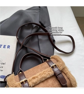 Close-up of brown plush faux fur crossbody bag with dark leather straps and gold buckle