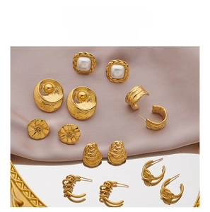 Detailed view of vintage gold stud earrings with pearls and hammered texture on pink silk