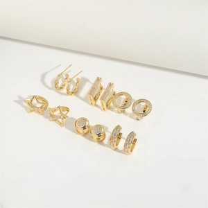 Detailed view of a six-pair gold pentagram and zircon earring set on white backdrop