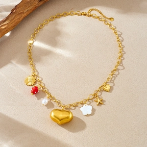 Goldene Edelstahlkette mit Herz-, Sonnenblumen-, Erdbeer- und Perlenanhängern auf beigem Holz