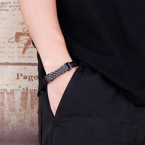 Men's black braided leather bracelet with wavy metal clasp shown on wrist
