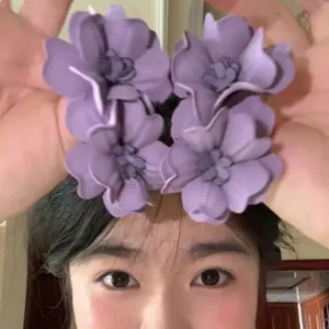 Detailed view of matte purple flower hair clips on model with multilayered petal design