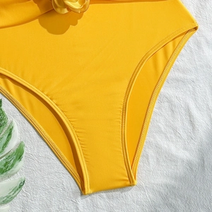 Detailed view of yellow swimwear with 3D floral accent and ribbed texture on fabric