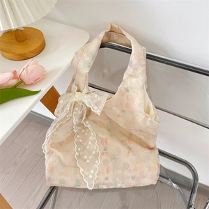 Detalle de bolso bordado crema con lazo de encaje delicado sobre una silla elegante