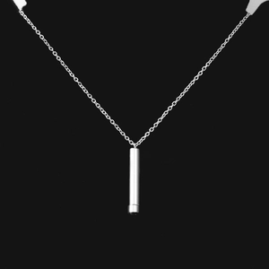 Close-up of polished silver cylindrical pendant on fine stainless steel chain necklace