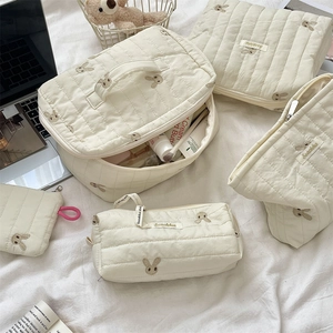 Detailed close-up of quilted cotton storage bags with cute rabbit embroidery patterns