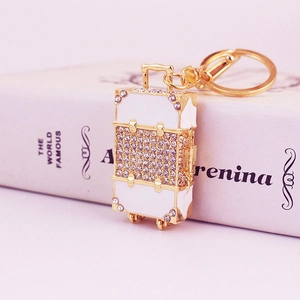 Sparkling rhinestone luggage suitcase keychain in gold finish with white enamel detail