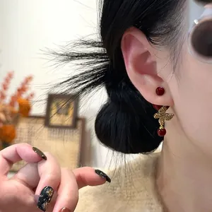 Gold plated butterfly stud earrings with red beads and zircon on a woman model