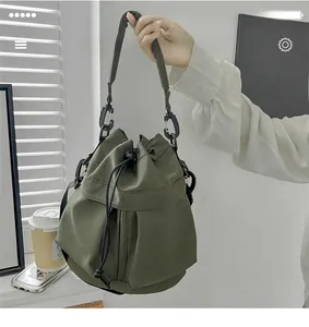 Detail of army green nylon bucket bag featuring a drawstring closure and side zipper pocket
