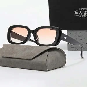 Detail shot of rectangular black frame sunglasses with pink gradient lenses and gray case