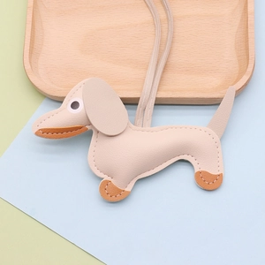 Close-up of beige lychee grain leather dachshund dog charm with white stitching