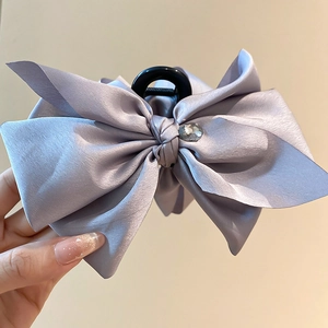 Detail of lavender satin bow hair claw clip with crystal center and silky texture