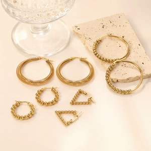 Set of gold stainless steel hoop earrings with beads on a warm aesthetic background