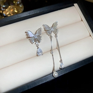 Detail of asymmetric butterfly earrings with butterfly wings, pearls and zircon tassels