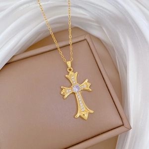Macro shot of gold cross necklace with clear crystals on elegant silk background
