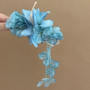 Close-up detail of a blue fabric flower hair clip with elegant dangling floral petal tassels