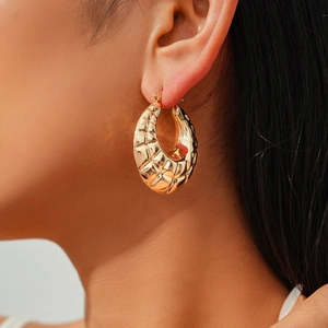 Close-up of gold hoop earrings with quilted texture shown on a female model