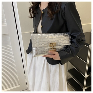 Silver envelope clutch featuring stone texture and a golden metal clasp held by a model