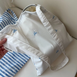Détail de la broderie de nœud bleu sur cabas en toile avec étiquette tissée simple