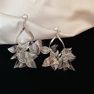 Macro detail of silver leaf drop earrings with white zircon on silk and velvet fabric