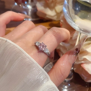 Close-up of pink round gemstone ring with pavé side stones on hand with elegant background