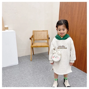 Detail showing plush bunny crossbody bag and printed lettering on a beige hoodie dress