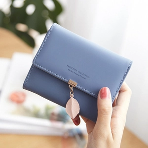 Detailed shot of a Morandi blue PU leather tri-fold wallet with a pink leaf pendant