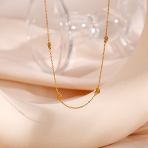 Detailed macro view of gold heart pendants on a fine chain over satin fabric