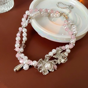 Detail of double-layer beaded necklace with pink flower charms and pearl resin drops