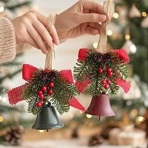 Christmas bell ornament with red bow, pine cones and berries held in hand for decor