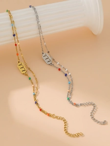 Dettaglio doppia catena oro e argento con ciondoli portafortuna 777 e perline colorate