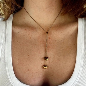 Golden stainless steel Y-shaped chain necklace with two heart pendants on female model